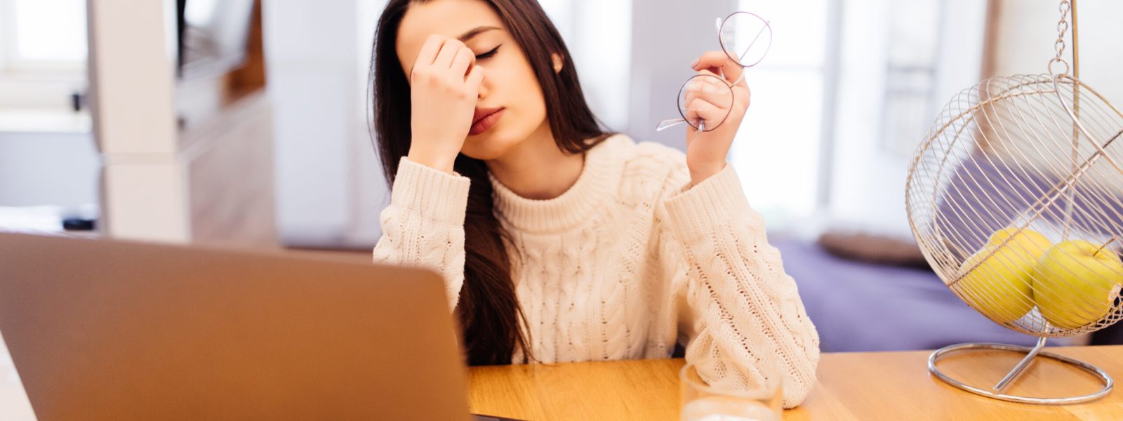pretty girl with lond black hair is working on her laptop and sitting at home at the table